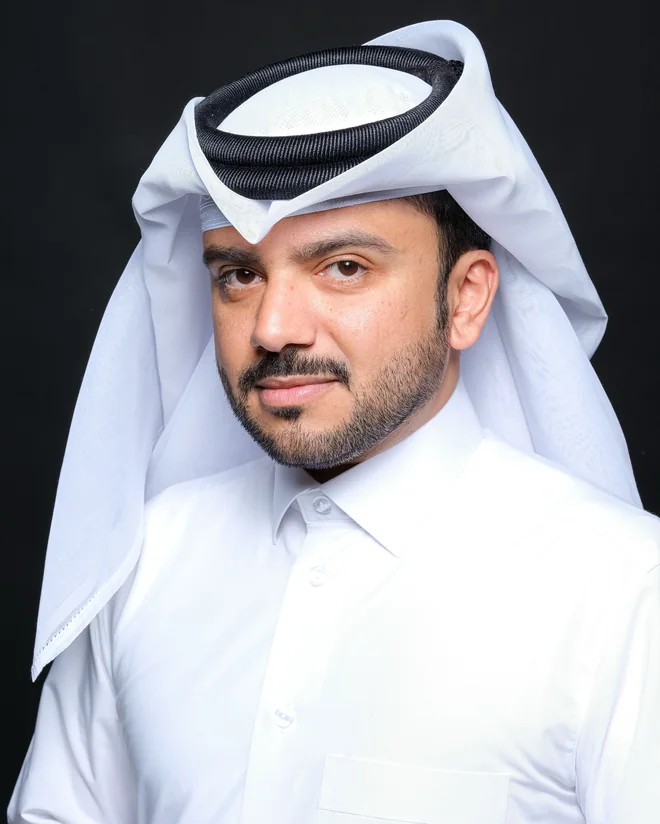 سعود المضاحكة، مبدع قطري، بالثوب الأبيض والغترة على خلفية استوديو سوداء