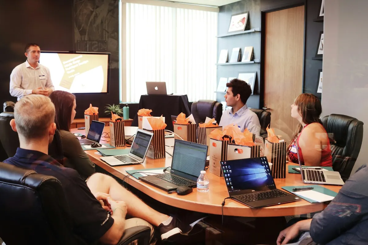 A man presenting to a seated team working on laptops during a campaign planning meeting