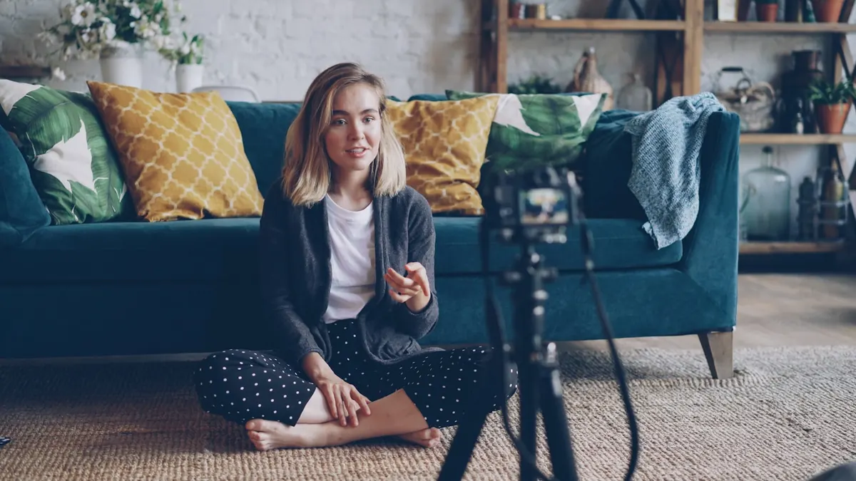 A content creator recording a video for her followers, speaking into a camera on a tripod